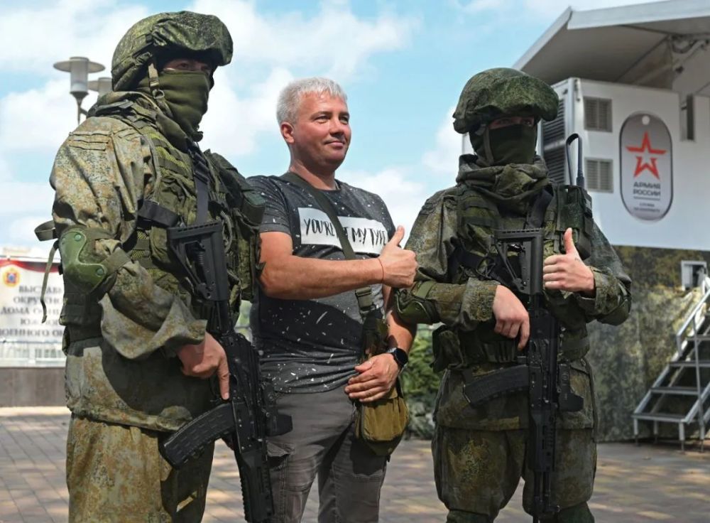 9月17日,一名男子与俄罗斯军人在征兵卡车外合影留念.