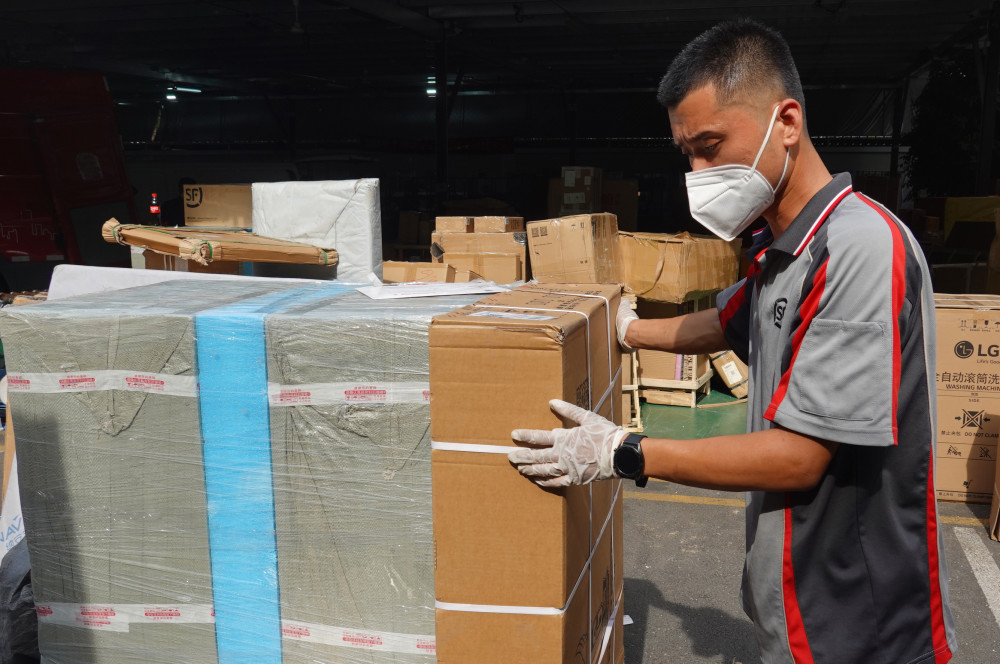 顺丰速运营业点,刘阔(左)和同事用传送带卸货并进行外包装消毒(2022年