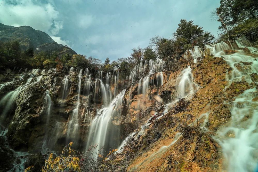 远处雪山耸立,近处瀑布环绕山涧,山石被流水冲刷得格外清秀.