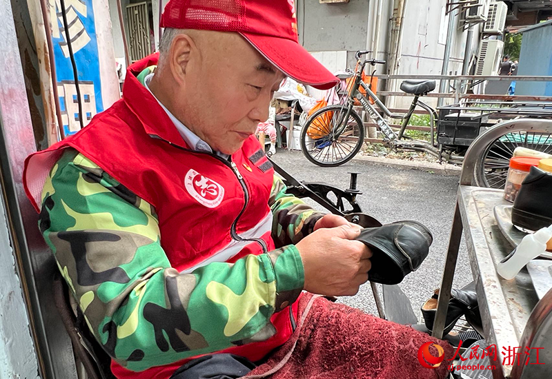 郭新宝坐在工作台前修理皮鞋.