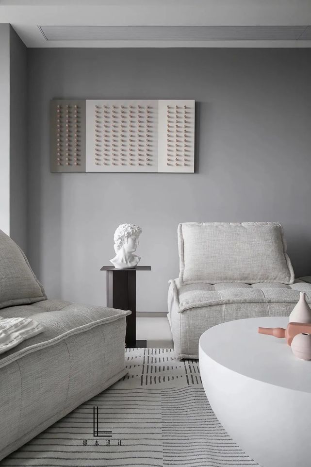 沙发墙以浅灰色的乳胶漆墙面,布置上淡灰色的布艺沙发,地毯与行闲