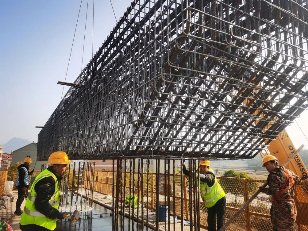 绑扎工作;在元胡大桥施工现场,汽车起重机挥舞长臂吊装盖梁钢筋骨架