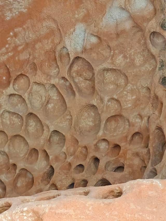 连片保存的蜂窝岩有三处,最大一处布局远看像一幅中国地图状,近看孔洞