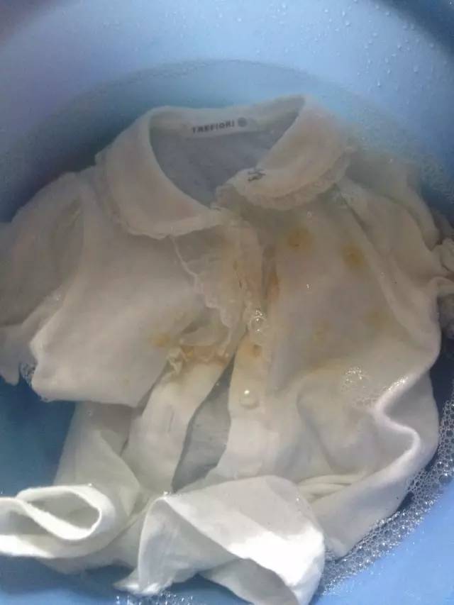 用棉签沾适量酒精涂在衣服污渍处,等到污渍溶解之后,揉搓冲净即可.