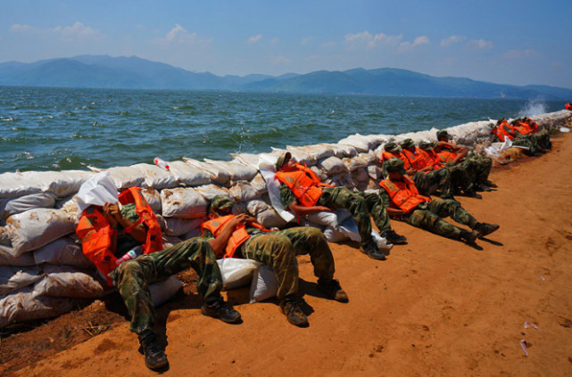 我们的解放军战士在经历了高强度的抗洪之后疲惫的在公路护栏一边倒下