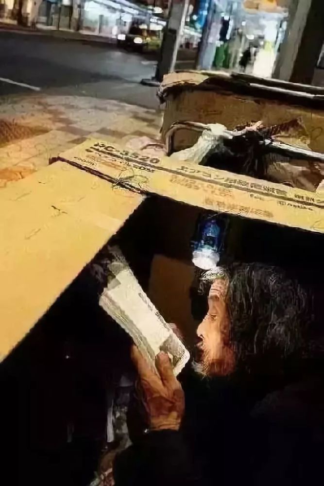 虽然在流浪,也要给心灵找到归宿,纸箱里的流浪汉在聚精会神地看书.
