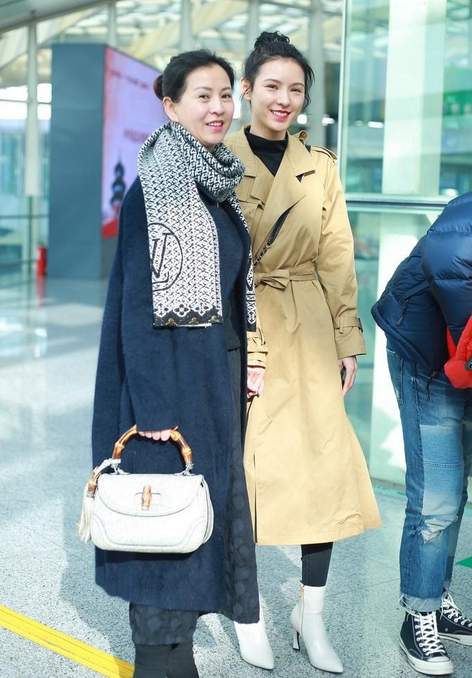 张予曦牵手母亲走机场,卡其色风衣搭丸子头甜