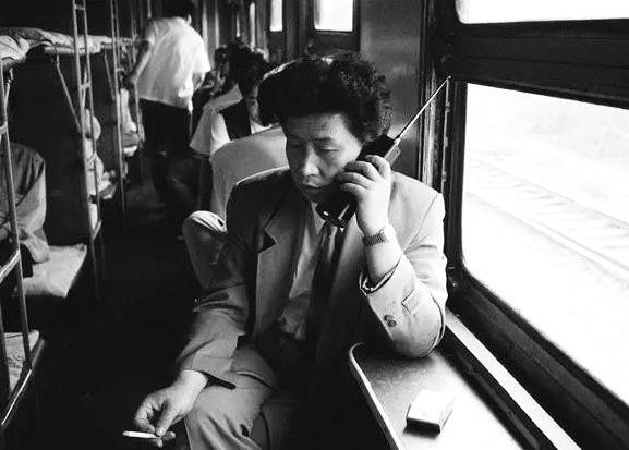 1994年，沈阳到大连的火车上，一名男乘客正在打电话，大哥大当时是一种身份的象征。