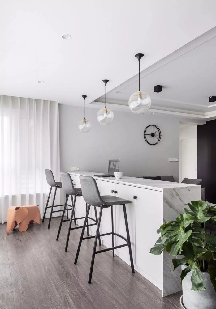 l形沙发以吧台为依靠,大理石纹路的台面结合上方透明玻璃球形吊灯