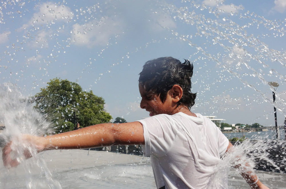 7月20日,在美国华盛顿,一名男孩在喷泉水池戏水降温.新华社记者刘杰摄