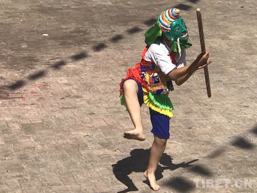 图为戴着面具手持木棍的舞者