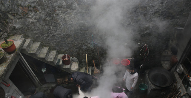 陕南山村一家杀两头年猪，亲戚朋友来帮忙，围着火盆吃杀猪饭