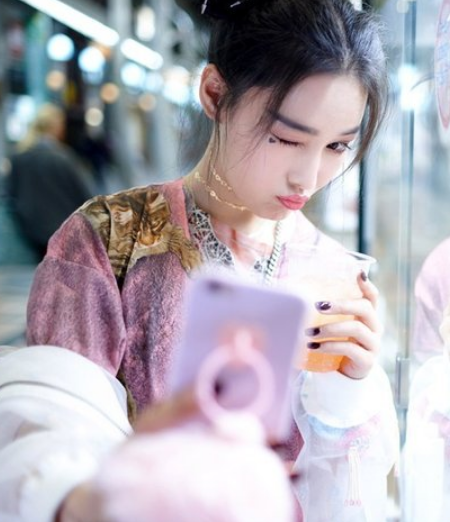 张馨予头扎双丸子头,身着粉色系宽松长裙,可爱不失时尚感