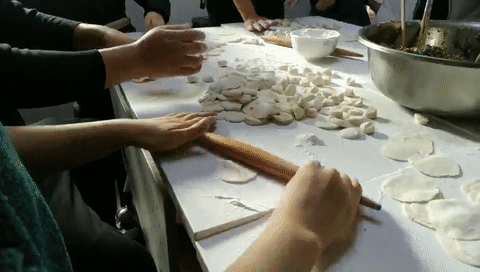 活动中,大家井然有序地分成若干组,有的擀皮,有的包饺子,相互之间传授