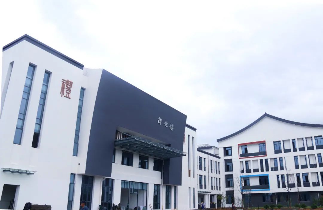 在鹿鳴小學遷建項目現場,工人們正在進行校園綠化,運動場地建設等作業