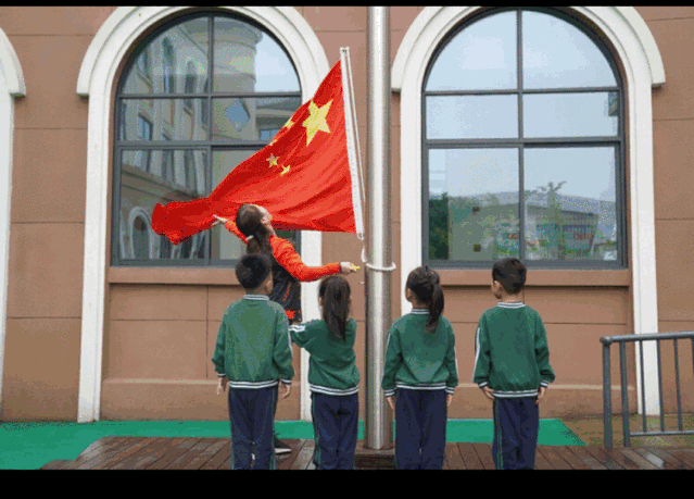所有孩子向国旗敬礼,鲜艳的五星红旗徐徐升起,师生注目飘扬的国旗肃然