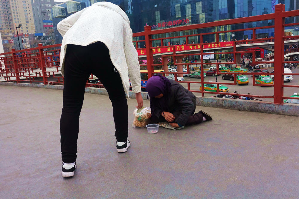 女子给跪地乞丐一袋麻花被乞丐扔进垃圾桶里现场图