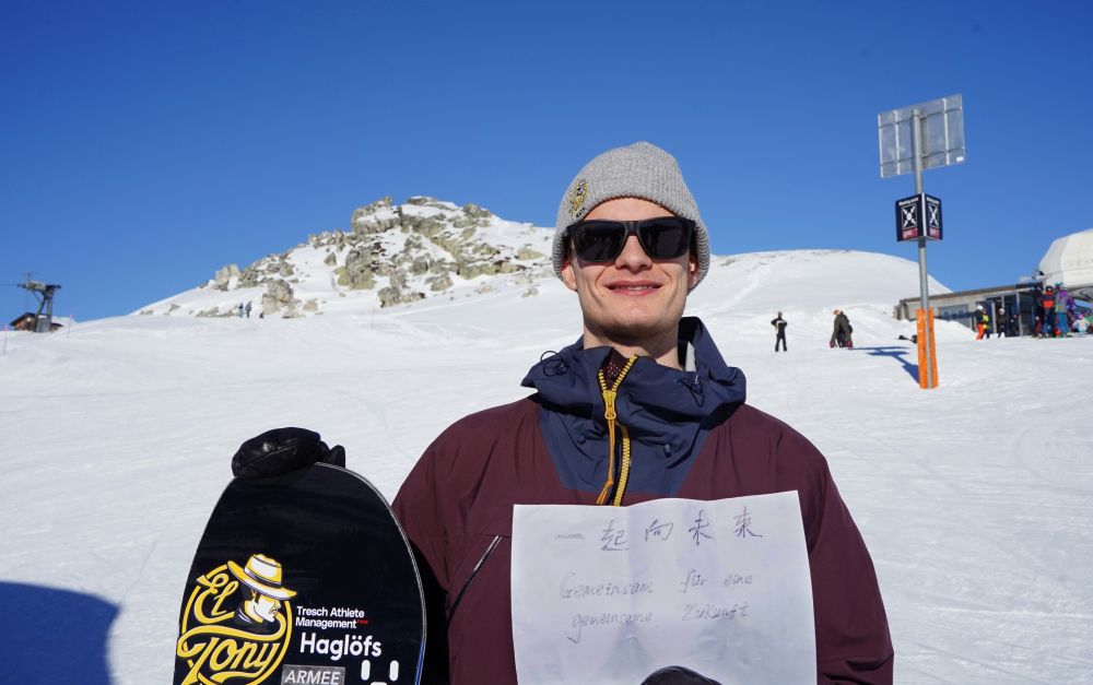 1月14日，在瑞士拉克斯，瑞士单板滑雪运动员约纳斯·伯西格尔手举“一起向未来”的主题口号，祝福北京冬奥会。新华社记者肖亚卓摄