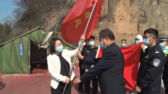 慰问活动中,县长李刚为坚守在各卡口的疫情防控人员发放了党章,县委