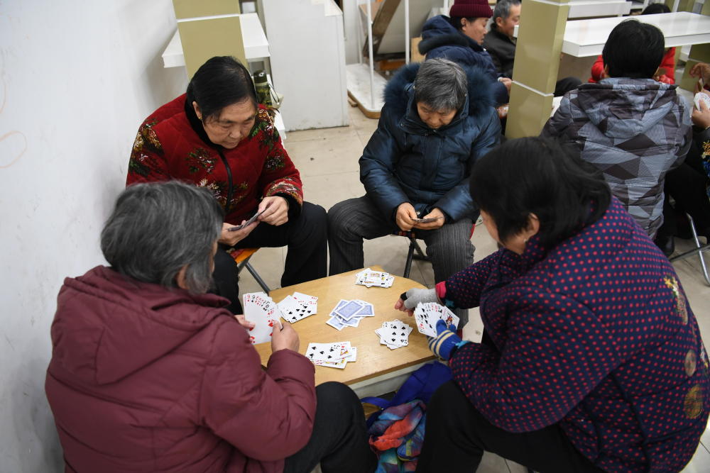 外面太冷,大爷大妈从家里端上板凳扎堆商场玩儿扑克