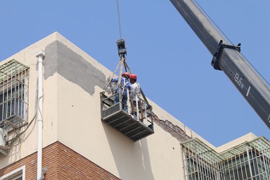 中心城區老舊小區及遠年住房改造開始,施工人員對房屋外簷整修