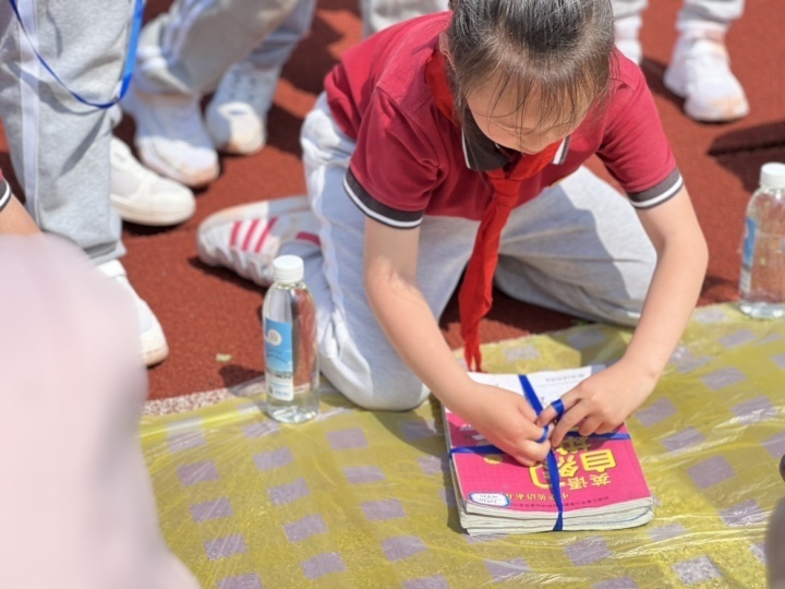 同學們熟練掌握捆書小妙招,看,將書本疊齊,用繩子以十字方式捆起來,先