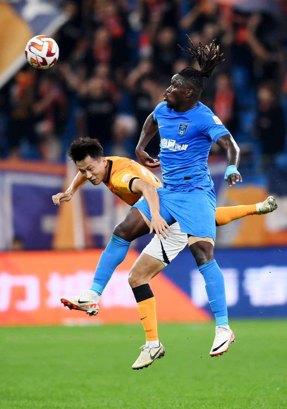 9月24日,青岛海牛队球员龙威(左)在比赛中与南通支云队球员罗马里奥