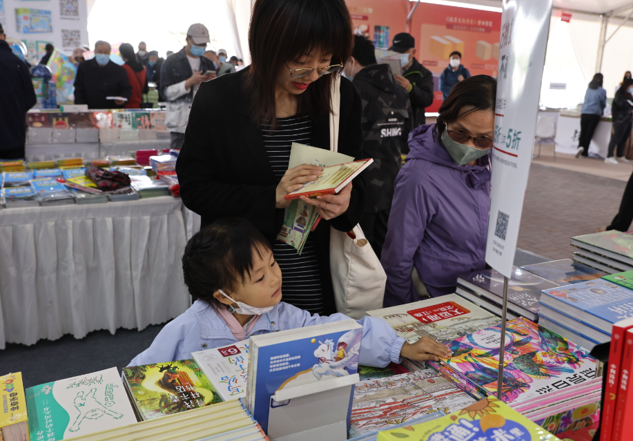 4月14日,读者在2023北京书市朝阳公园主展场阅读选购图书.