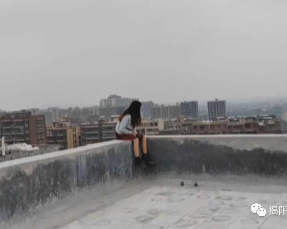 这名女子坐在高楼天台边缘