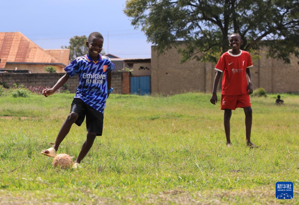 在卢旺达基加利,两名男孩在布盖塞拉国际机场路升级改造路段旁踢足球