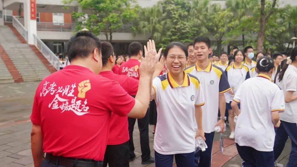 在江门一中,考生面带笑容,与老师击掌后走进考场.