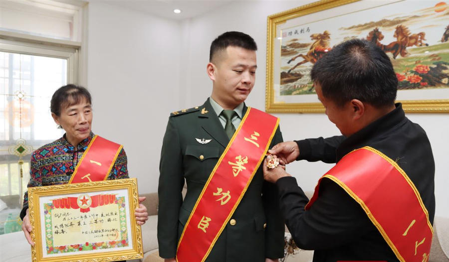 工作人员为三等功臣胡广和其家属佩戴绶带,送上喜报和奖金,并合影留念