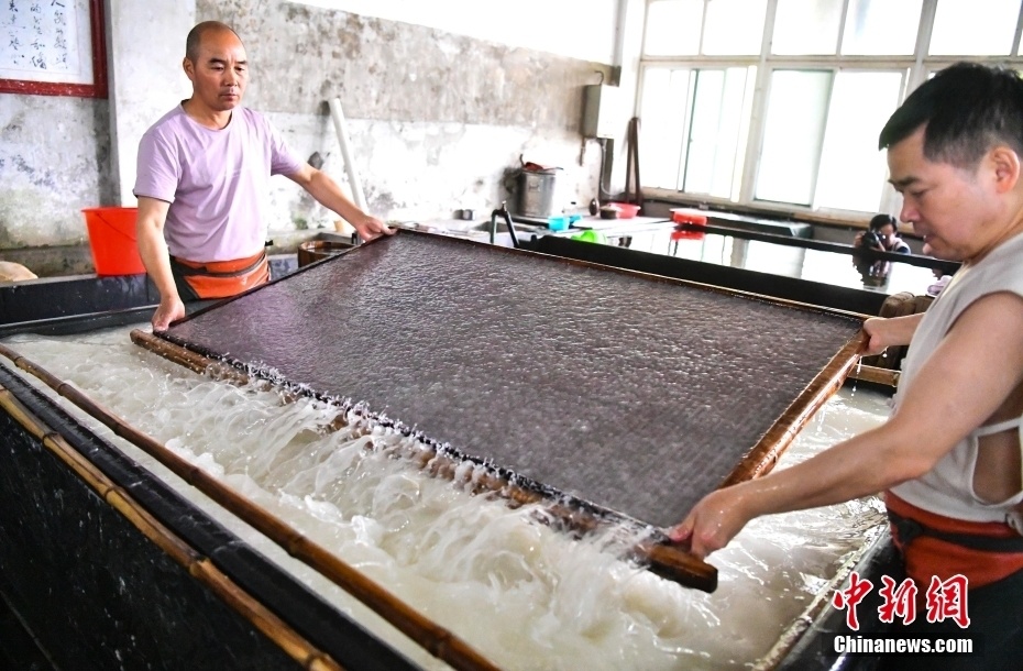 宣纸工匠展示宣纸制作流程的纸帘工艺.