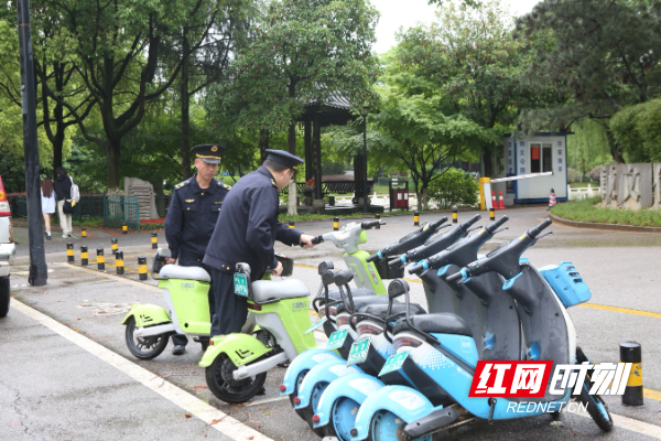 网格执法队员将乱停放的共享单车摆放至指定位置.
