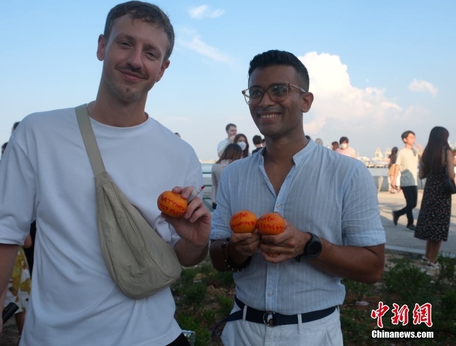 中新社记者 陈悦 摄一位外国游客展示写有联系方式的柑橘.