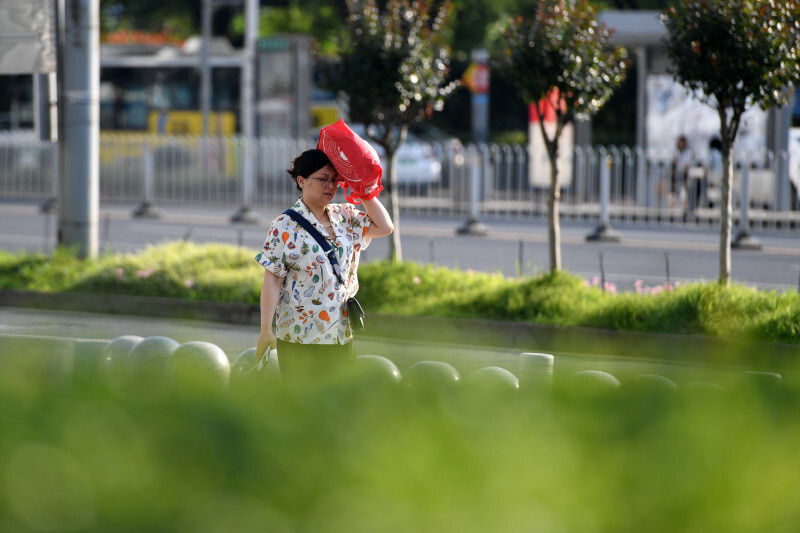 5月28日下午,開福萬達廣場附近,過往的行人用手遮擋陽光. 均為長沙晚