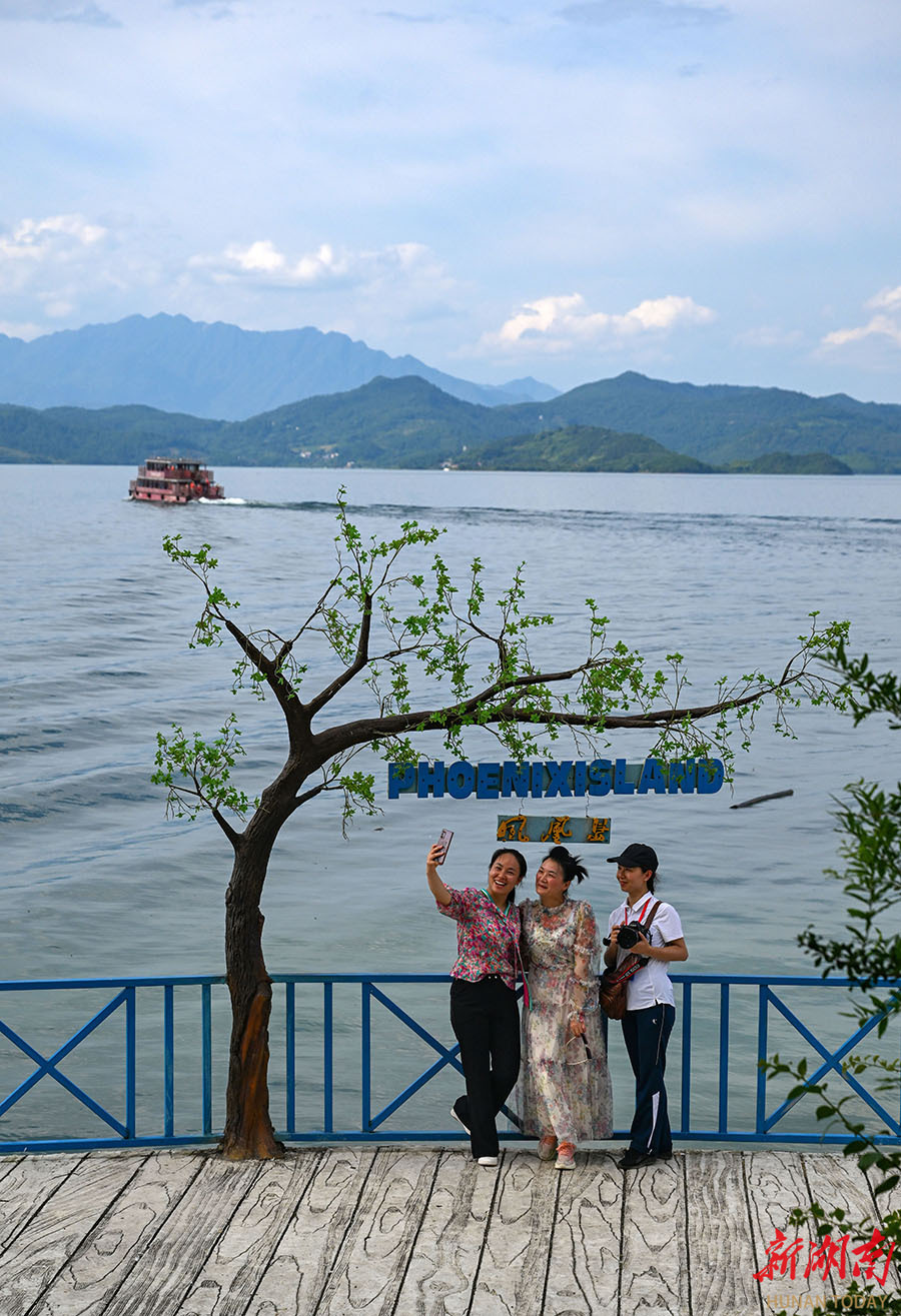 6月22日,游客在资兴市东江湖五岛一村凤凰岛景区游玩赏湖.