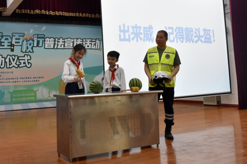 在清城区新北江实验学校里,普法团队接过旗子,为"交通安全百校行"普法