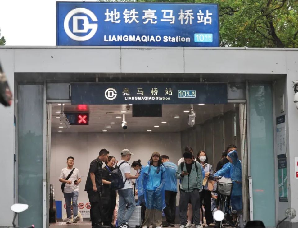 亮马桥地铁站,工作人员为市民免费发放雨衣.