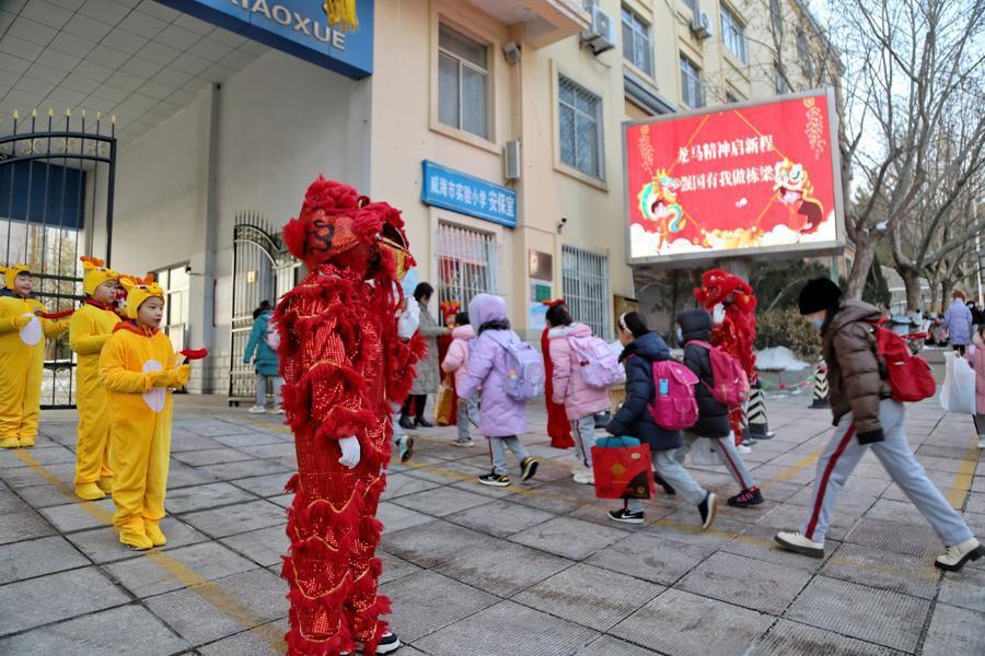 在威海市实验小学门口,由老师和同学们扮演的吉祥龙和如意狮,手持