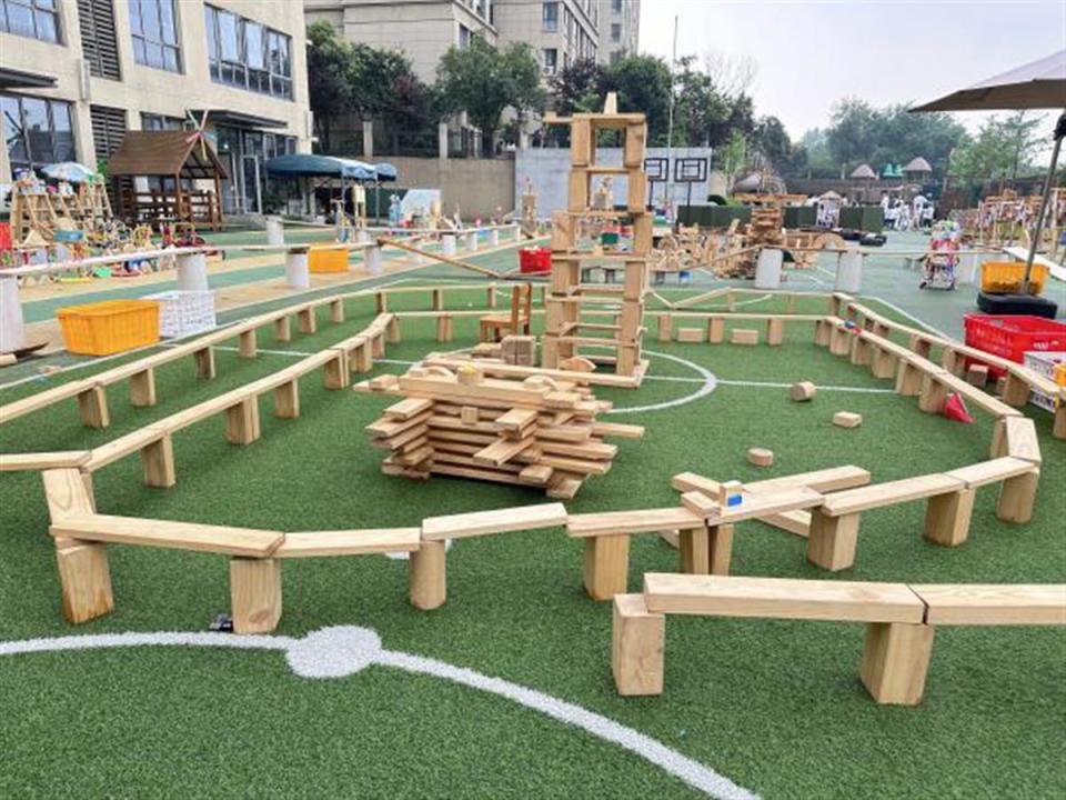 武汉市青山区第一幼儿园绿地花园的操场上堆满了不同形状的木制积木