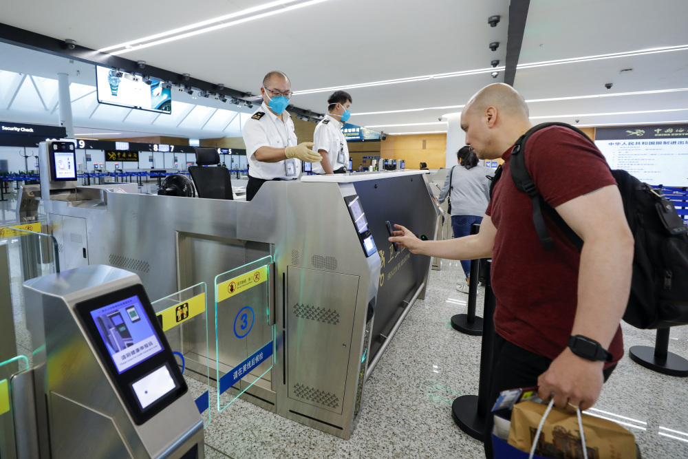 6月21日,在成都天府国际机场,成都海关关员(左)指导一名外国旅客刷