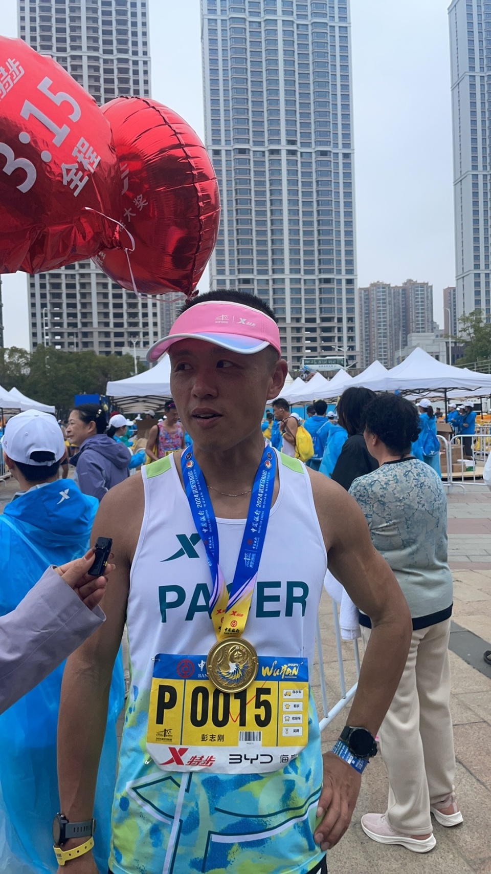 2024武汉马拉松官方配速员彭志刚在终点处向记者展示刚刚领到的奖牌