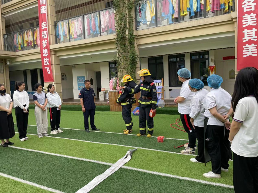 教职工讲解并操作幼儿园消防栓,干粉灭火器和一次性防火面罩的使用