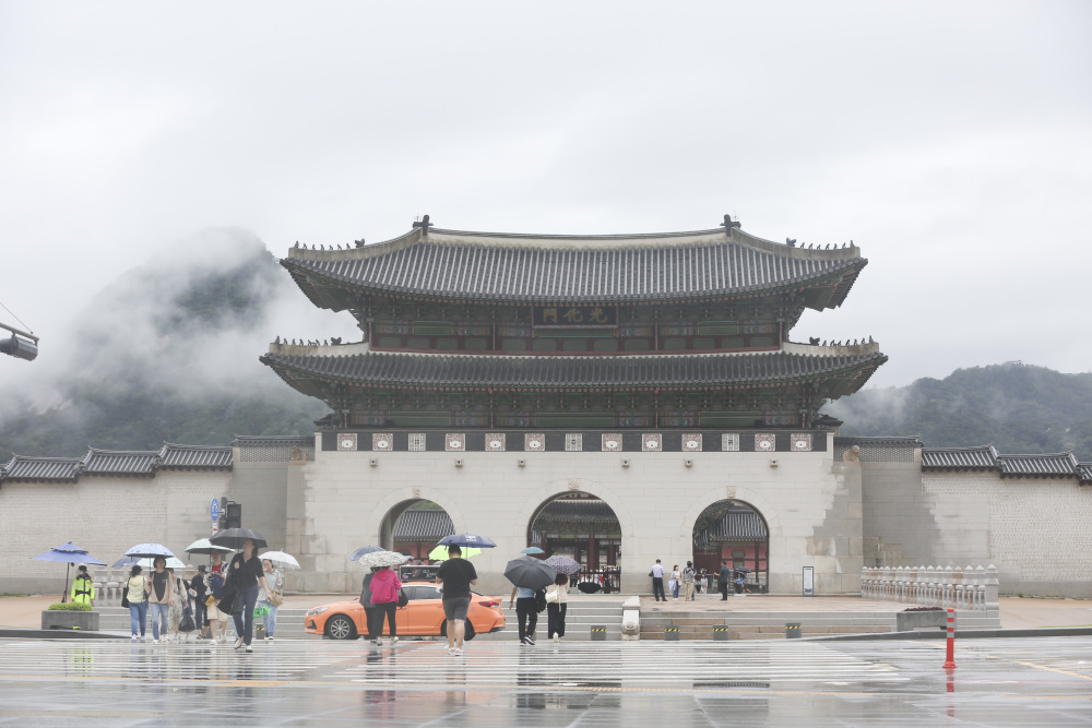 7月18日,游客冒雨游览韩国首尔的景点