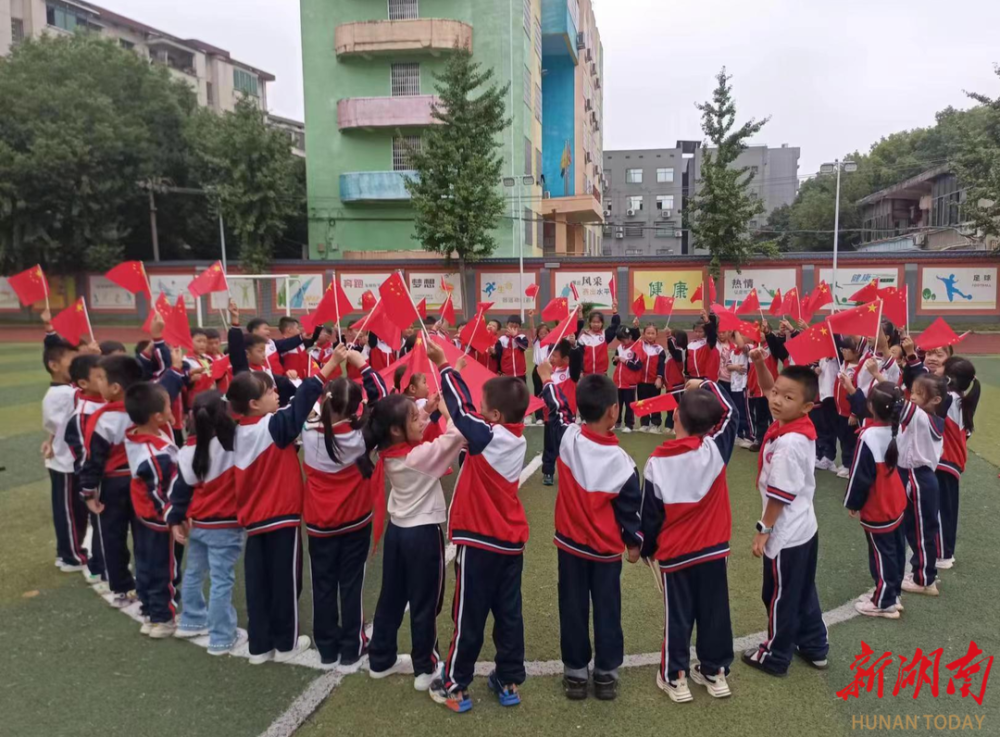 活动中,孩子们有的双手捧着鲜红的国旗,唱着《绣红旗》;有的向国旗行