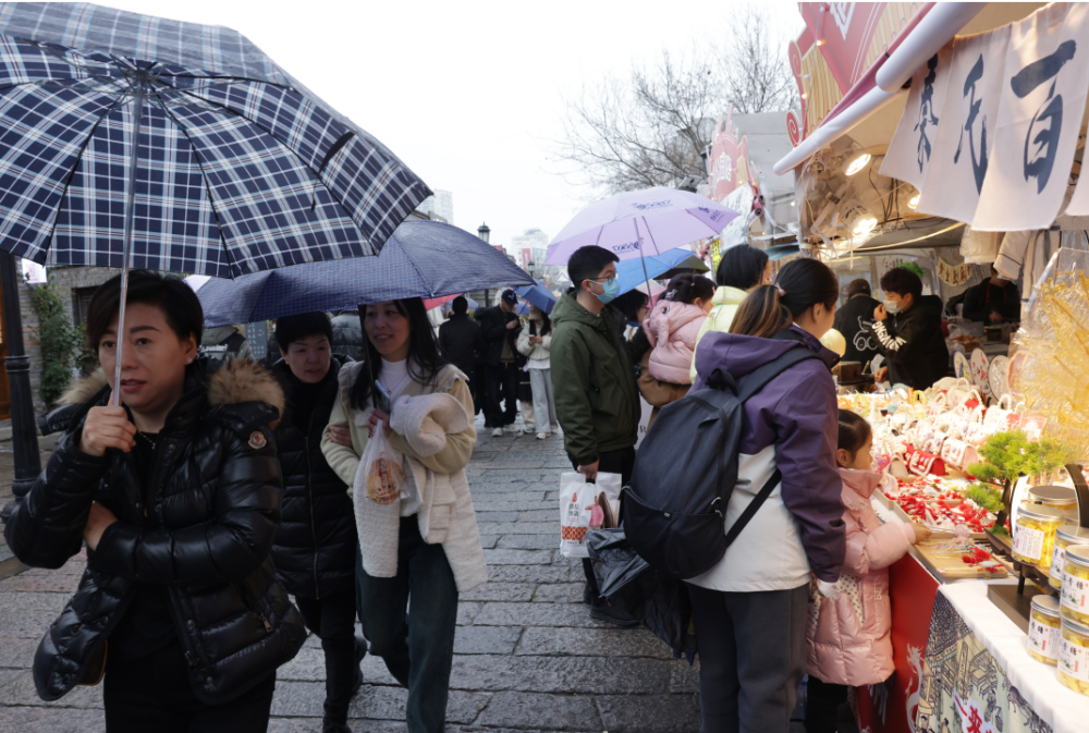 立春,绵绵细雨阻挡不了市民逛街的热情