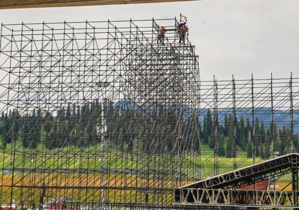 记者走进2024新疆那拉提紫金音乐节舞台搭建现场,看见工人正分布在