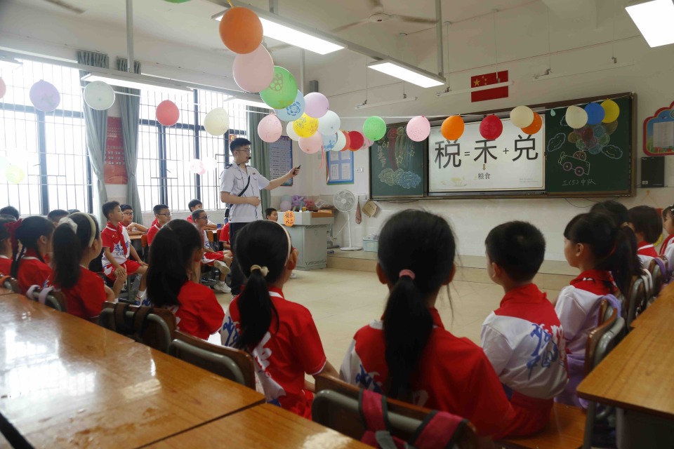 在江门台山市东晖小学的税法小课堂,同学们在税务干部的引导下通过