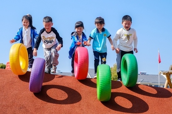 浙江省长兴县水口乡中心幼儿园,小朋友在山坡上进行趣味滚轮胎比赛